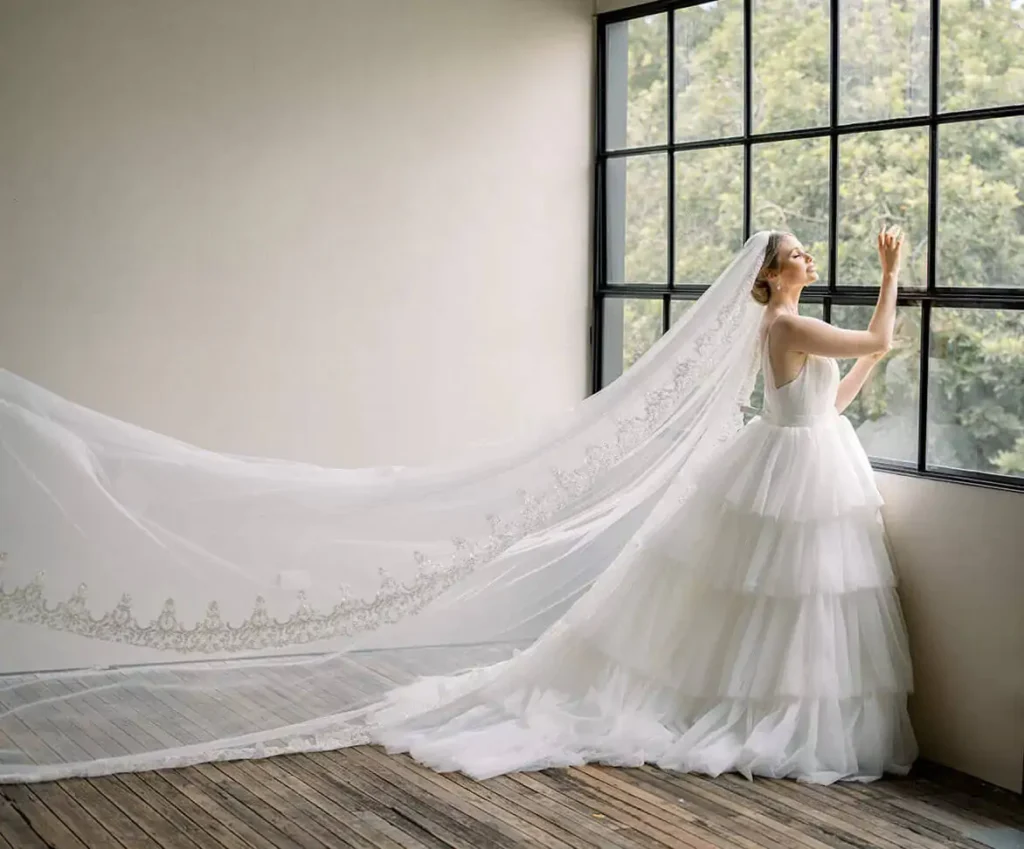 woman standing near to window wearing a wedding dress and veil