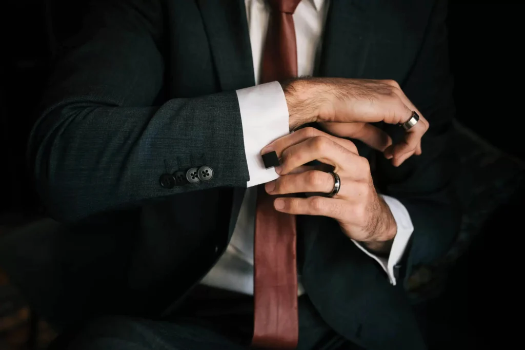 Man in a suit holding cufflinks